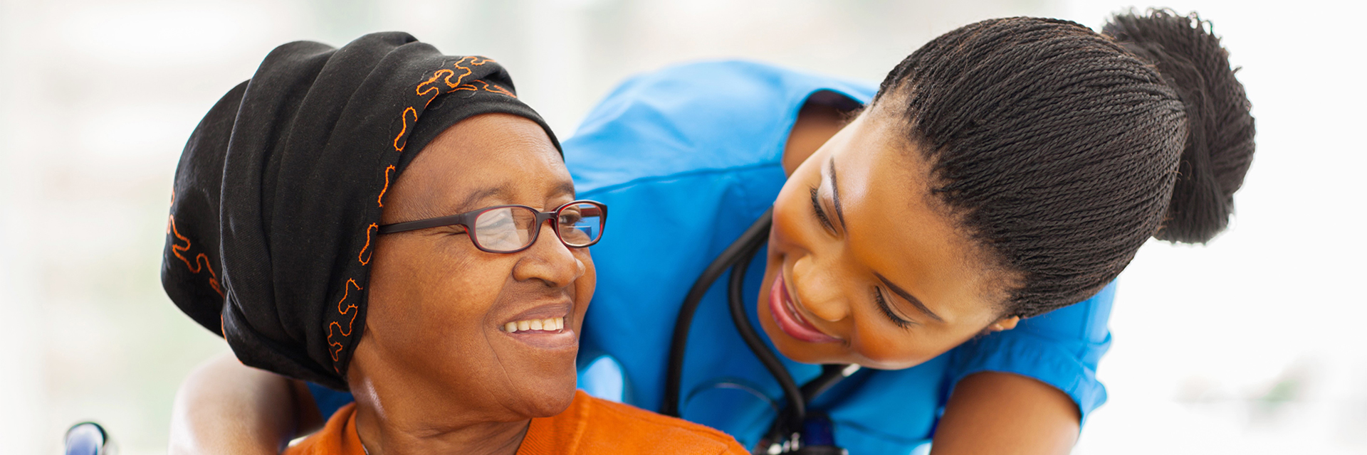 nurse in blue scrubs hugging woman in orange top